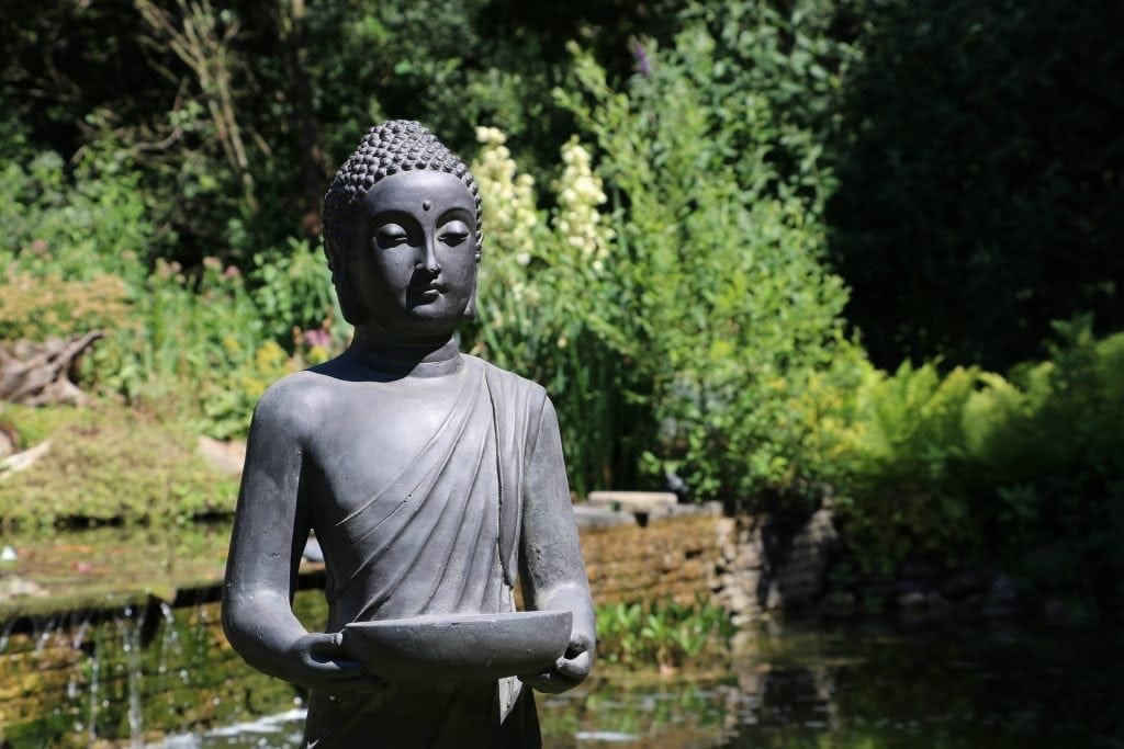 boeddha beeld staand donker grijs voor in de tuin